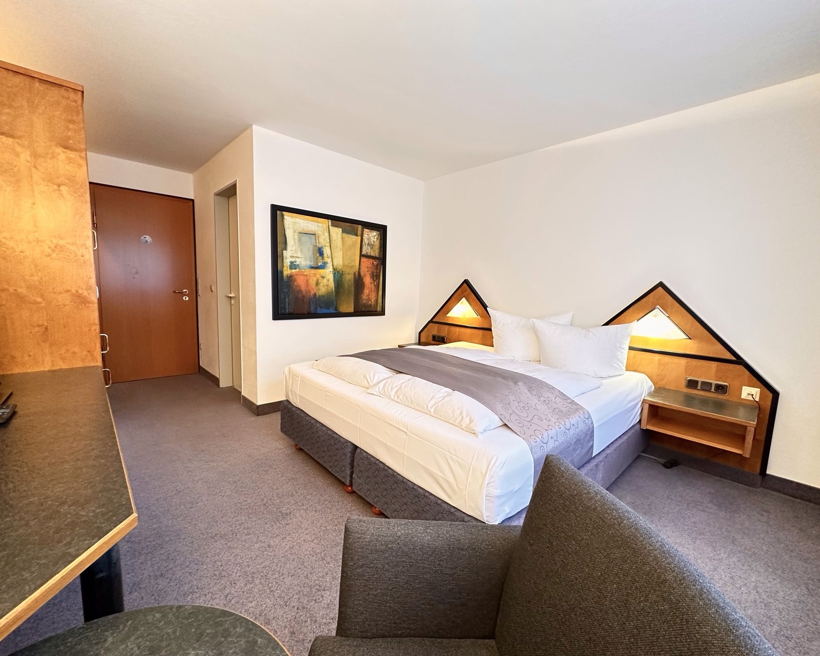 Komfortzimmer im Hotel Residenz mit frisch bezogenem Bett und Sessel